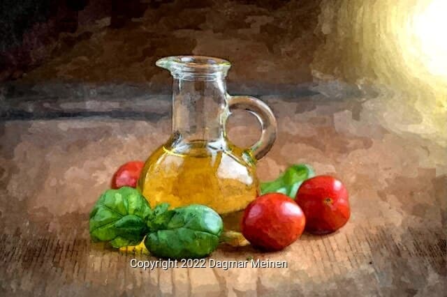 Auf einem alten Holztisch steht in der Mitte ein Kännchen mit Öl. Außenherum sind rote Tomaten und frische Basilikumblätter drapiert.